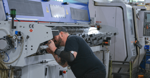 CNC maintenance technician performs preventive maintenance on a barfeeder
