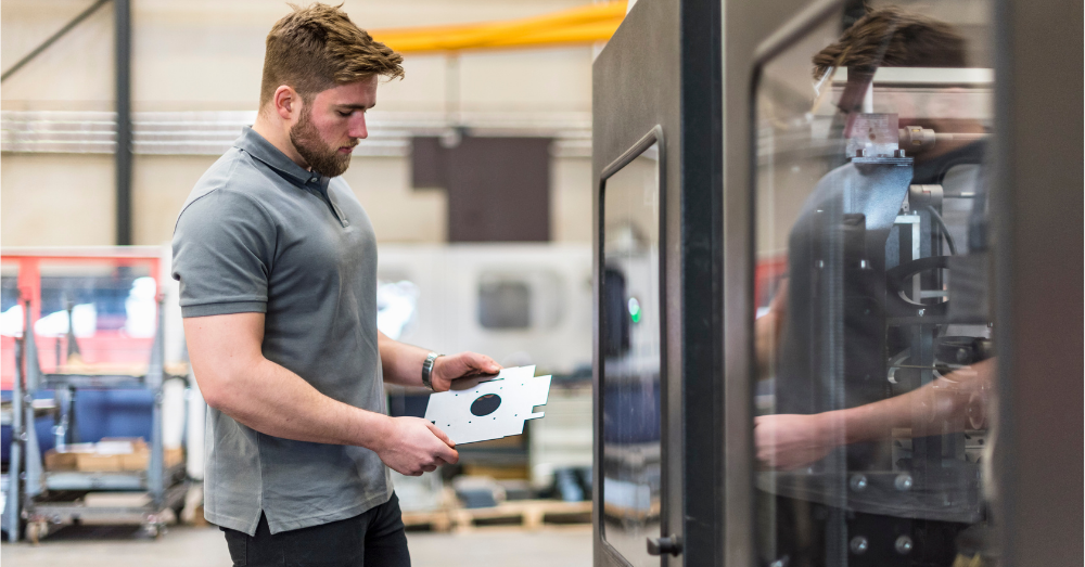 manufacturing engineer examines a part as it comes off a CNC mill