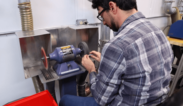 Finishing Specialist deburrs a part on a grinding wheel