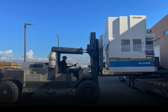 Operator lifts CNC mill onto flatbed truck